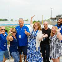 A group holding up the "Laker for a Lifetime" hand gesture excitedly.
